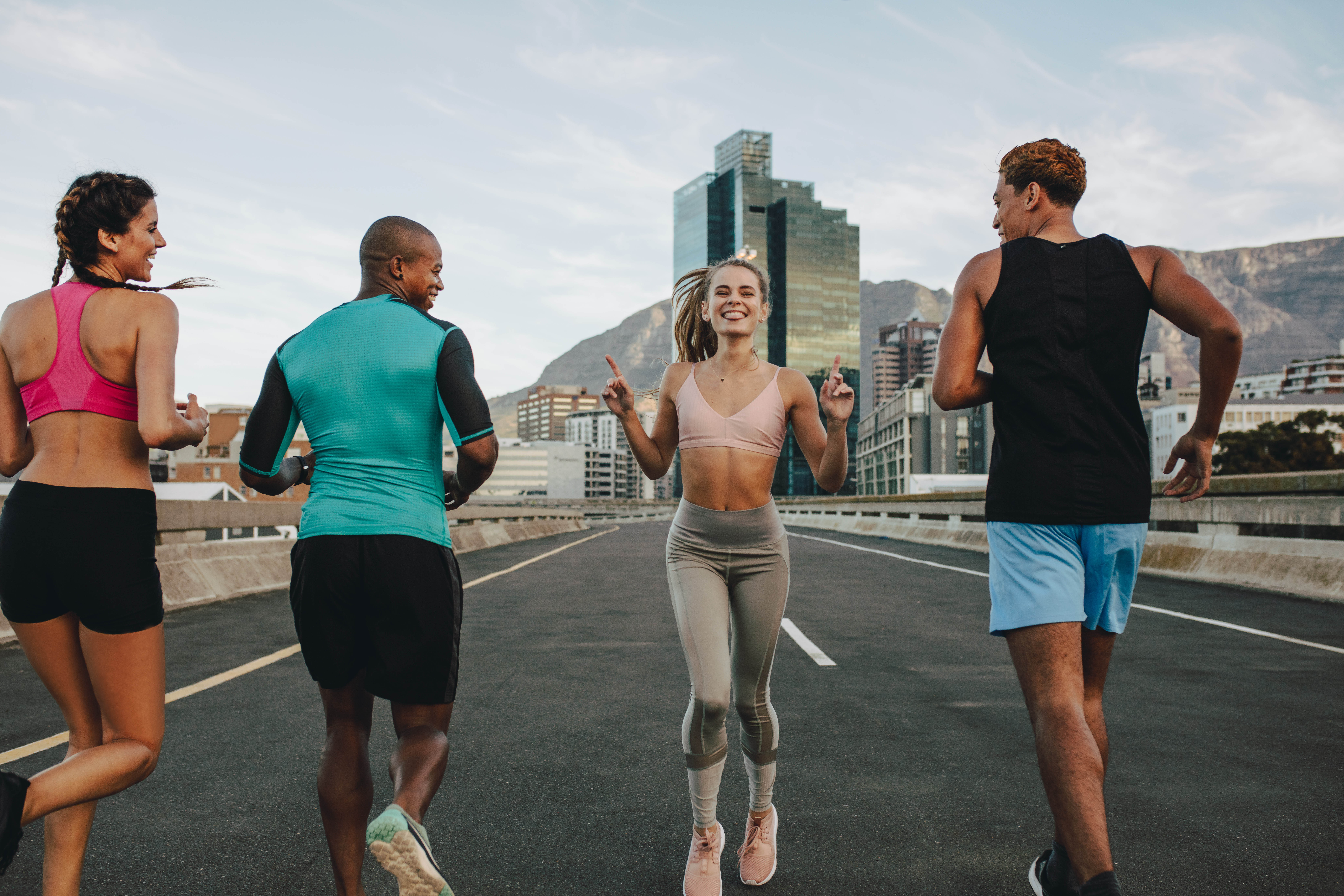 Group of 4 young fit people, one woman is running backwards and facing the camera Group of 4 young fit people, one woman is running backwards and facing the camera